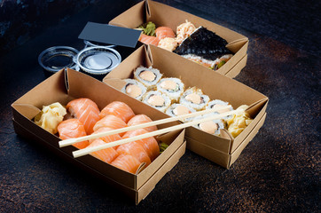 Tasty sushi rolls in disposable kraft paper boxes, sauces, chopsticks. Sushi for take away or...