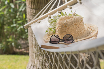 Straw hat on a hammock in a sunny summer day. Rest in the garden. Summer time fun