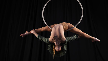 Professional circus aerialist performs splits on the ring. young, athletic, flexible gymnast on a...