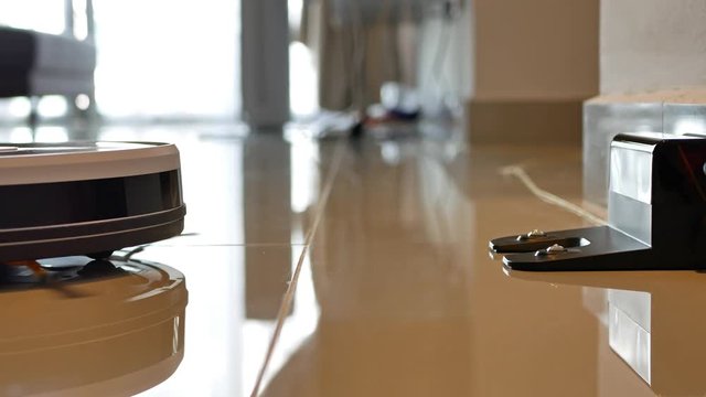 Close-up view of the robotic vacuum cleaner go back to the charging dock automatically when battery runs low.