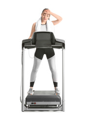 Sporty young woman resting after training on treadmill against white background