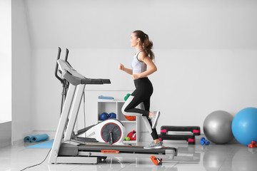 Sporty young woman training on treadmill in gym