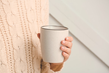 Woman with cup of tea on grey background, closeup