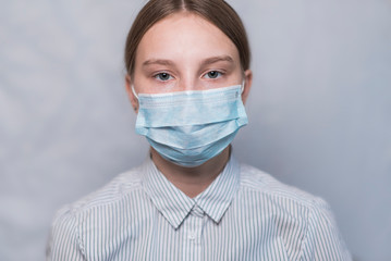 teenager girl 12-15 years old, face covered in medical mask, close-up portrait, caution virus disease flu and disease, stay home, stop pandemic of coronovirus covid 19.