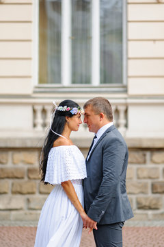 Wedding photo session on the background of the old building. The bride and groom hold each other's hands.Rustic or boho style wedding photography