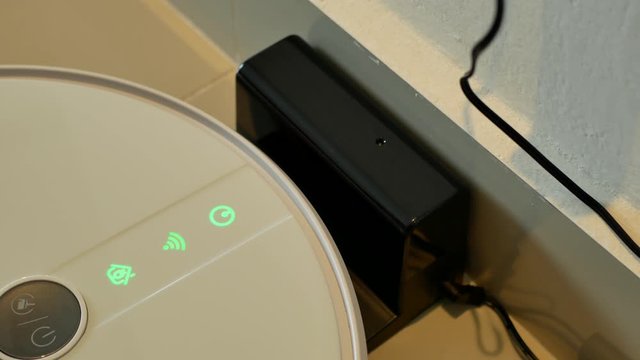 Close-up view of the robotic vacuum cleaner charging at the dock.