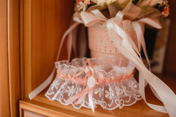 The bride wears lingerie and jewelry. Garter of the bride. Beautiful legs of the bride in a wedding dress.
