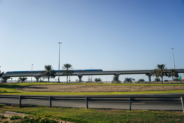 A metro train rides over a bridge over a city where palm trees grow | UNITED ARAB EMIRATES, DUBAI - 17 OCTOBER 2017.