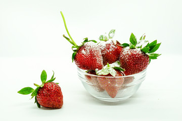 Fresh strawberries in a bowl. Fresh juicy strawberries with powdered sugar in glass bowl isolated on white background.