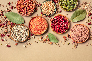 Legumes assortment, shot from the top on a rustic brown background with a place for text. Lentils,...