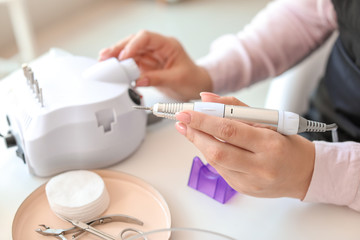 Manicure master working with modern milling cutter in beauty salon, closeup