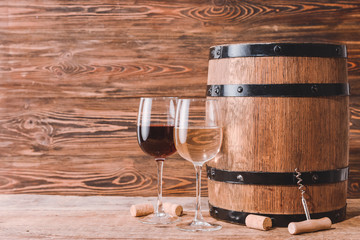 Wooden barrel and glasses of wine on wooden background