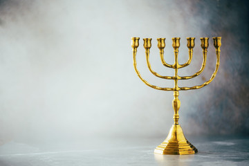 Golden hanukkah menorah on grey background. Jewish holiday banner with copy space. Ancient ritual religious candle menorah