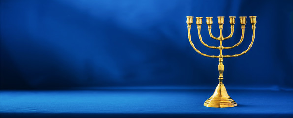 Golden hanukkah menorah on blue background. Jewish holiday banner with copy space. Ancient ritual religious candle menorah - obrazy, fototapety, plakaty
