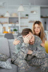 Depressed soldier sitting on sofa with his wife. Young marine having PTSD.	