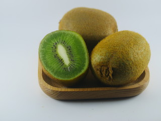 A slice and two kiwi on wooden plate in the white background