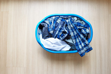 Clothes in blue plastic laundry basket.