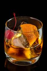 old fashion cocktail in a glass of rox on a black background