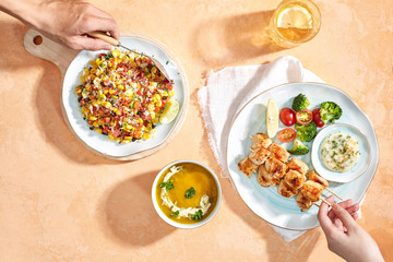 Combo menu set : Mexican salad, pumpkin soup and grilled chicken skewers. Hand talent. Flatlay angle