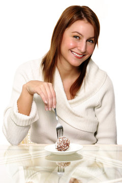 A woman using a fork to eat a chocolate ball cake