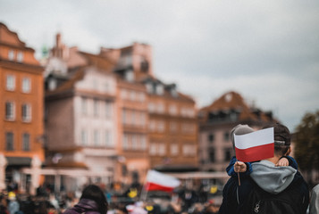 A small kid holding the Polish flag.