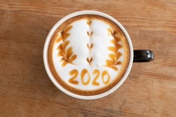 hot coffee with foam milk art 2020 on wooden table, latte art coffee