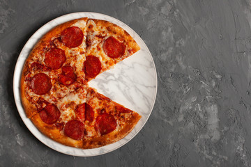 Tasty pizza. Pepperoni pizza on grey concrete background with copy space. Top view of sliced pepperoni pizza. 