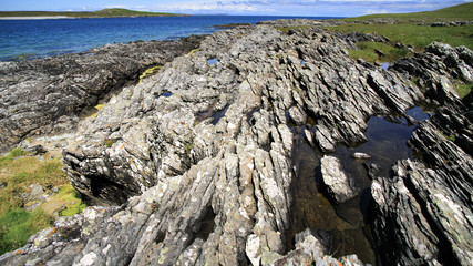 Panoramaaufnahme von Erosionspuren, die sich in parallelen Linien von Kamera weg über einen Küstenfelsen ziehen