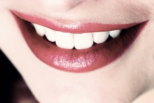 An up-close picture of a woman's red lips and white teeth