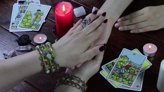 A Gypsy fortune teller reads her hand by candlelight and Tarot cards. The palmist tells fortunes by the lines of the hand
