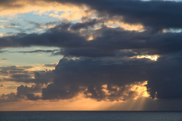 Sonnenuntergang über dem Meer mit Sonnenstrahlen, die durch ein Wolkenloch scheinen