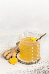 Ginger tea with honey and lemon in glass. Warm revitalizing beverage used to help relieve cold and flu symptoms.