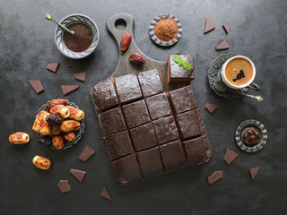 Chocolate brownie cake with dates and coffee cup, dessert on black background
