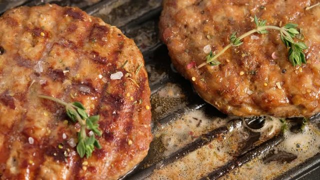 Grilled hamburgers on the grill. Burger cutlet is cooked in a grill pan, steam, smoke, fire. Butter is melted. Grill food.
