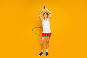 Full length body size view of nice funky slim thin cheerful cheery glad guy spinning plastic circle waist pilates shaping having fun isolated over bright vivid shine vibrant yellow color background