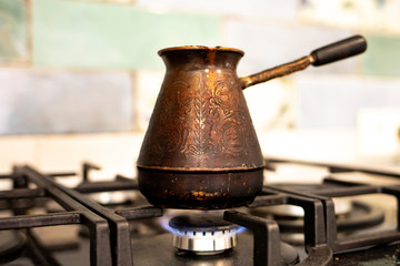 Vintage Turk for coffee on a stove in the interior of the house.