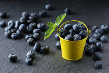 ripe blueberries in a small bucket on a gray background