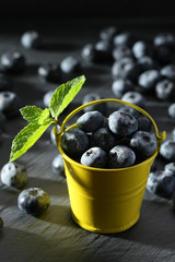 ripe blueberries in a small bucket on a gray background