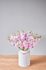 Bouquet of Beautiful lilac mattiola. Spring flowers in vase on wooden table. Flowers delivery.