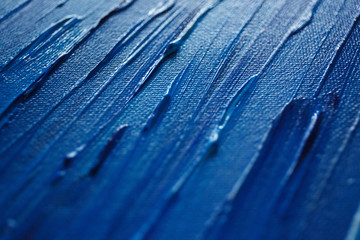 
A thick layer of acrylic or oil paint in different shades of blue on canvas, shot on macro. abstract blue background