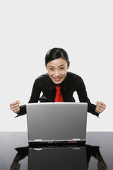 Businesswoman cheering while using laptop