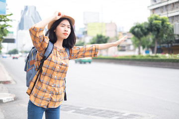 Asian girl tourists Standing on the roadside To wave a taxi for travel in the capital