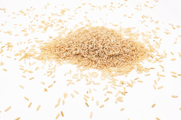 A small pile of long-grain brown rice lies on a white background, a table in the laboratory for analysis or examination with space for writing.