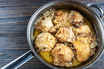 Appetizing tasty fried chicken thighs in a pan on wooden boards, top view, rustic style. Homemade food concept.