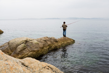 Fototapeta na wymiar Fisherman on sea fishing on the rocks sea