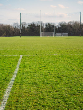 Markings on a training field in focus, Two goalposts for Irish National sport out of focus, Vertical image.