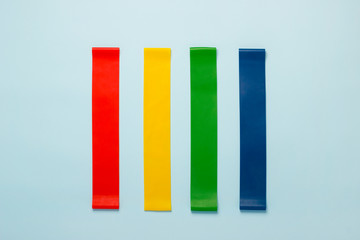 Multicolored fitness elastic bands on a blue background . The concept of a healthy lifestyle and home fitness workouts.