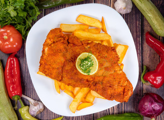 gourmet Chicken Schnitzel on a White Plate with Lemon, fried potatoes, and small butter, on a...