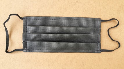 Black face mask on a yellow-orange background. Medical item for protection against coronavirus by airborne droplets. Flat lay foto.