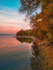 Obraz premium colorfully clouds at sunset. lake reflecting sky and forest 